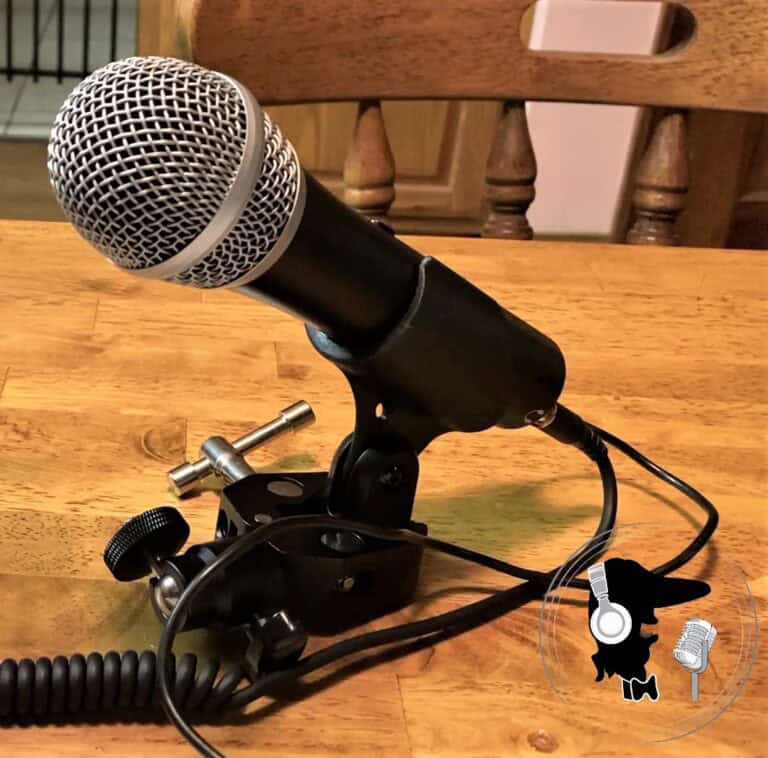 Photo of a black microphone in a clamp device sitting on a wooden desk