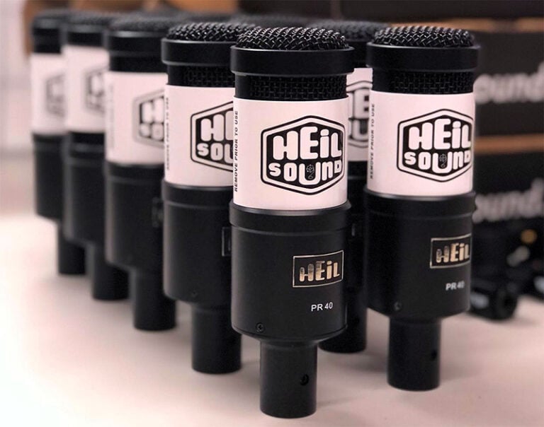 Photo showing a diagonal view of 10 new Heil-PR40 microphones arranged on a white table top.