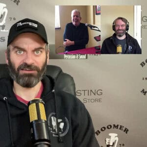 A photo of Drew speaking into a black and gold colored microphone with an insert showing a split screen of himself and another man during an online conference call in the upper right-hand corner