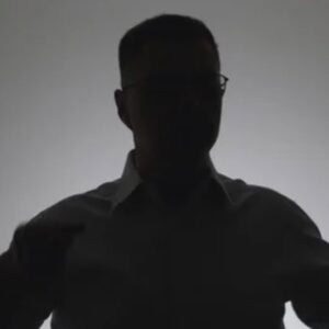 Shadow outline photo of a man with short hair in front of a light gray background.
