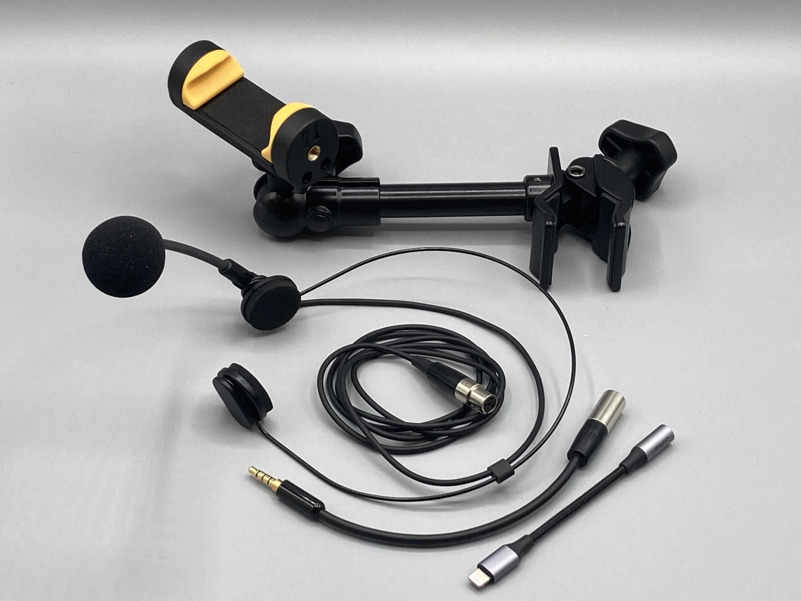 Photo of some microphones, connectors, wireless systems, and device holders displayed on a table top
