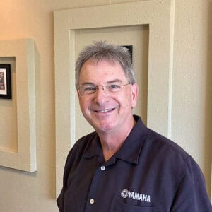 A photo of Wes Kreitz smiling in front of a cream-colored wall.